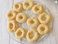 Un plato transparente muestra rosquillas caseras esponjosas, listas para hornear.