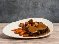 Delicioso plato de cola de toro en salsa, acompañado de patatas rústicas y zanahorias glaseadas.