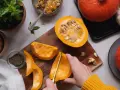 Manos cortando calabaza para deliciosas recetas. Ingredientes frescos listos para cocinar.