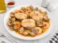 Merluza a la cazuela con gambas, almejas y guisantes en una salsa sabrosa.