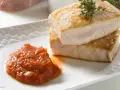 Dos trozos de atún a la plancha apilados, con una cucharada de salsa de tomate y una ramita de tomillo.