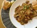 Fricandó, hecho con la parte de la ternera llamada "espalda", servido en plato blanco con pan.