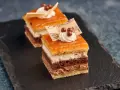 Deliciosa tarta San Marcos en porciones, con capas de bizcocho, crema y cobertura anaranjada, decorada con nata y notas musicales de chocolate.