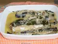 Caballa en escabeche servida en una fuente blanca, con cebolla, laurel y un líquido dorado.