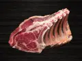 Lomo bajo de vacuno crudo con costillas, sobre fondo oscuro de madera.