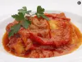 Bacalao a la riojana, un plato tradicional con trozos de pescado blanco cubiertos en una salsa roja de pimientos y tomate, adornado con perejil fresco.