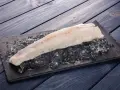 Filete de pescado rosado fresco sobre hielo picado en una tabla negra, listo para cocinar.