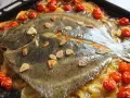 Rodaballo al horno con tomates cherry y láminas de ajo, sobre una cama de hinojo y patatas. Un plato delicioso y aromático.