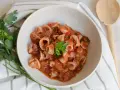 Deliciosos chipirones en salsa de tomate, servidos en un cuenco de cerámica, decorados con perejil fresco.