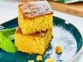 Dos porciones de bizcocho de calabaza espolvoreadas con azúcar glas, acompañadas de hojas de menta fresca en un plato azul.