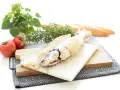 Lubina a la sal lista para servir, acompañada de tomates frescos, romero y pan rústico.