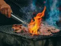 Carne a la parrilla, humeante y chispeante, lista para una deliciosa parrillada barbacoa.