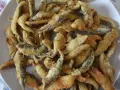 Un plato blanco lleno de boquerones fritos crujientes, listos para disfrutar.