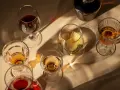 Copas de vino tinto y blanco, y una botella oscura, con reflejos de luz. El vino abierto se pone malo, mejor disfrutarlo pronto.