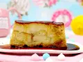 Un trozo de pan de calatrava con caramelo líquido, sobre un plato blanco, con merengues de colores y un limón al fondo.