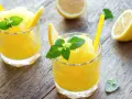 Refrescante granizado de limón, perfecto para un día caluroso. Servido en vasos con rodajas de limón y hojas de menta.