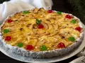 Deliciosa tarta de manzana cubierta de almendras laminadas y cerezas rojas y verdes. El borde está cubierto de coco rallado.
