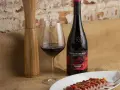 Una copa de vino seco, una botella de Ramón Bilbao Rioja y un plato de atún sellado, listos para una cena.