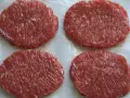 Cuatro hamburguesas de carne poco hecha, listas para cocinar y disfrutar.