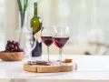 Dos copas de vino tinto, uvas y galletas, listas para disfrutar de un momento especial con los productos de la cooperativa do val.