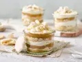 Postres en vaso con capas de bizcocho, crema y dulce de leche, coronados con merengue y polvito canario.