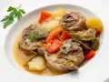 Cordero guisado receta tradicional con patatas, zanahorias y alcachofas en un plato blanco.