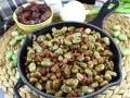 Habas tiernas salteadas con trocitos de jamón en una sartén de hierro fundido, un plato tradicional y delicioso.