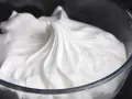 Merengue italiano esponjoso y brillante en un bol de cristal, listo para decorar postres.