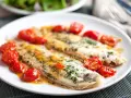 Dos filetes de lenguado a la plancha, servidos con tomates cherry salteados y perejil picado.