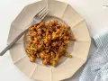 Coliflor glaseada, una de las mejores recetas con coliflor. Servida en plato beige con tenedor plateado y servilleta a cuadros.