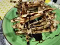 Berenjenas fritas en forma de bastones, bañadas en miel oscura, servidas en un plato verde.