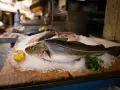 Pescado fresco en hielo, listo para deliciosas recetas de bacalao. Limón y perejil acompañan.
