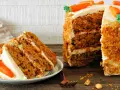 Deliciosa tarta de zanahoria con glaseado cremoso y decoraciones de zanahorias. Una rebanada ya servida en un plato.