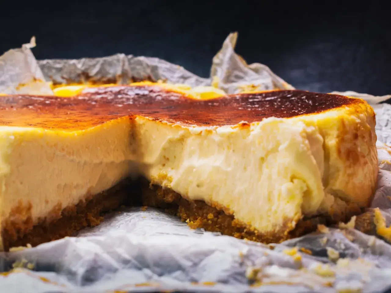 Tarta de queso cremosa con base crujiente y cobertura dorada, recién salida del horno.