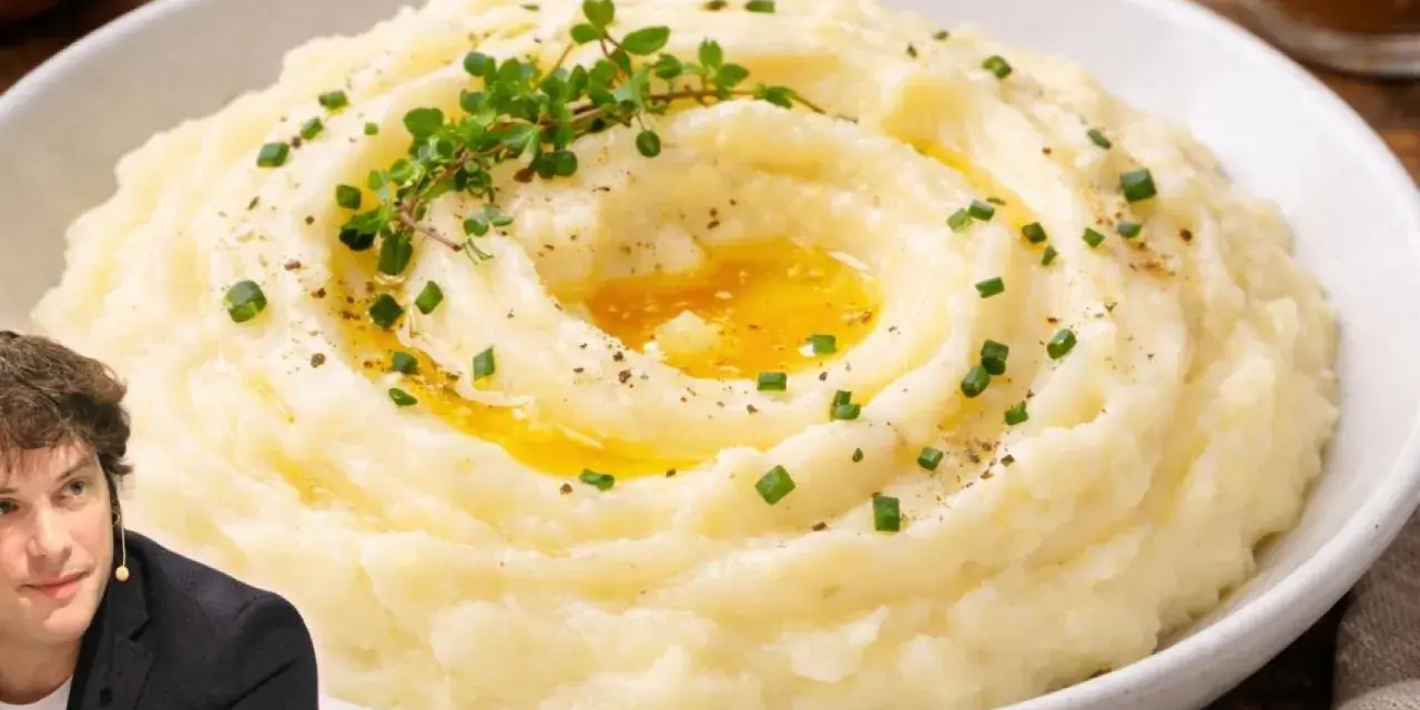 Un hombre sonríe junto a un plato de cremoso puré de patatas, adornado con hierbas frescas y un chorrito de mantequilla derretida.