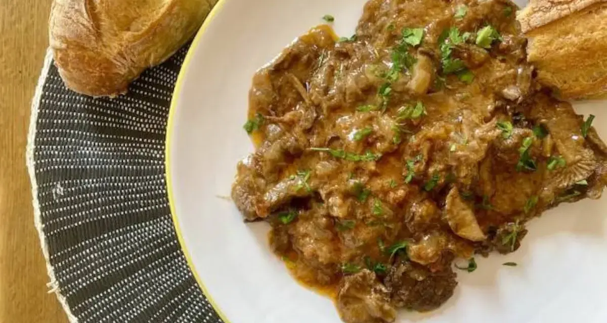 Fricandó, hecho con la parte de la ternera llamada "espalda", servido en plato blanco con pan.
