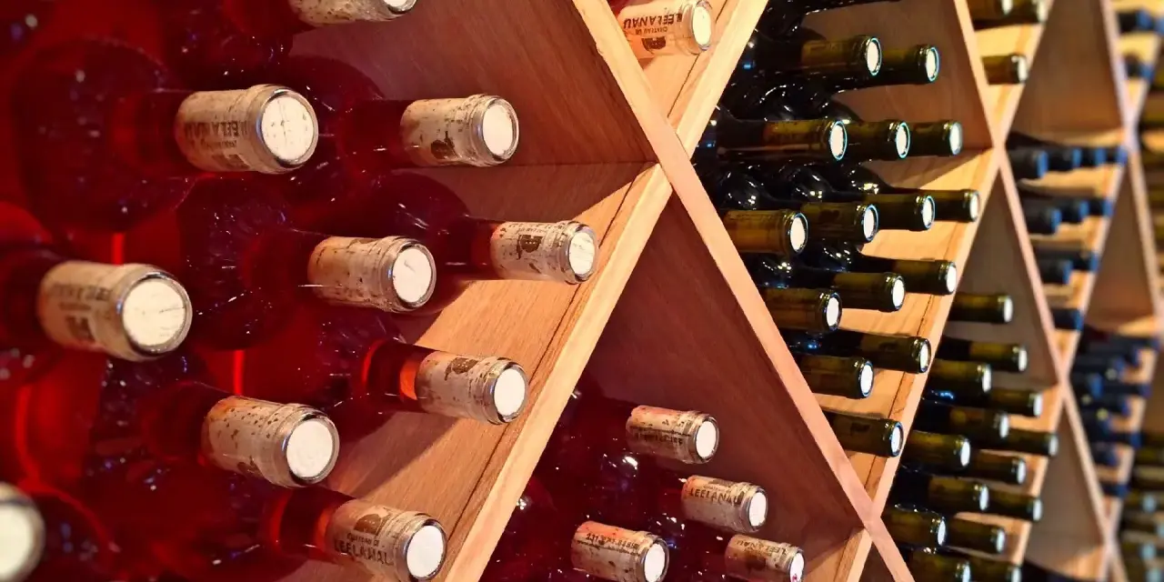 Estanterías de madera llenas de botellas de vino tinto y blanco. Un lugar donde se guarda el vino, listo para ser disfrutado.