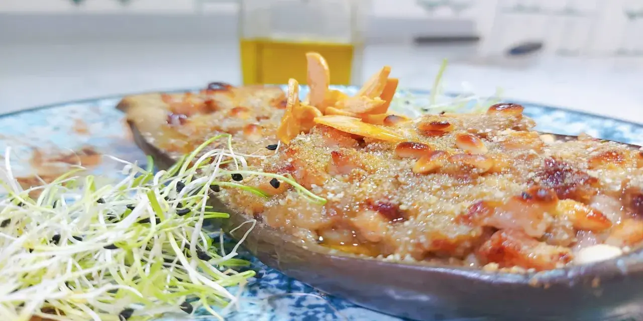 Berenjenas rellenas gratinadas con piñones y brotes frescos, un plato delicioso y nutritivo.