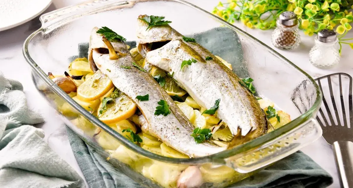 Pescadilla al horno con patatas, limón y ajo, recién salida del horno. Un plato sencillo y delicioso.