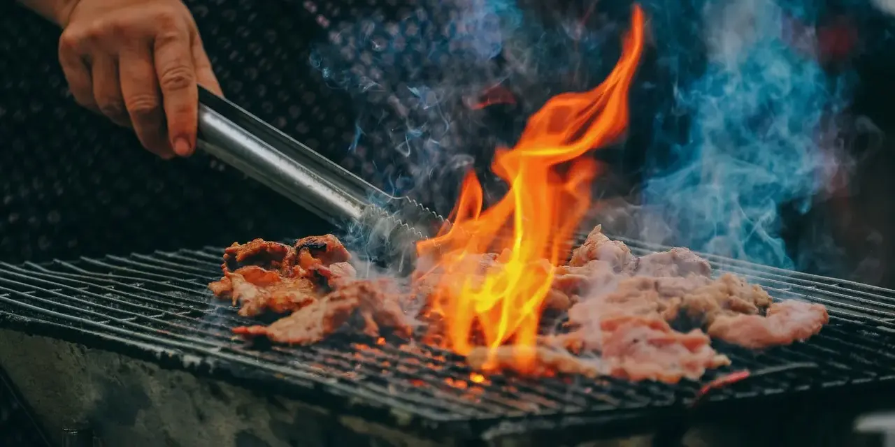 Carne a la parrilla, humeante y chispeante, lista para una deliciosa parrillada barbacoa.