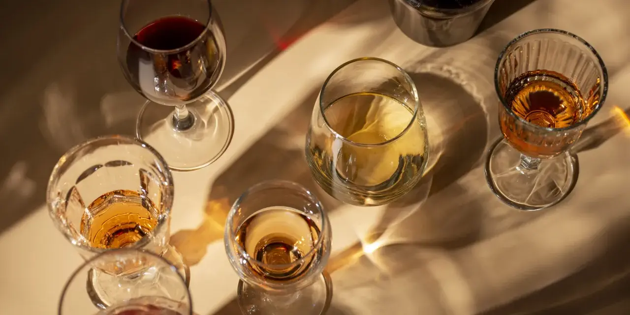 Copas de vino tinto y blanco, y una botella oscura, con reflejos de luz. El vino abierto se pone malo, mejor disfrutarlo pronto.
