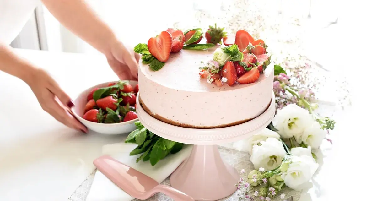 Deliciosa tarta de fresa decorada con fresas frescas y menta, lista para ser servida.