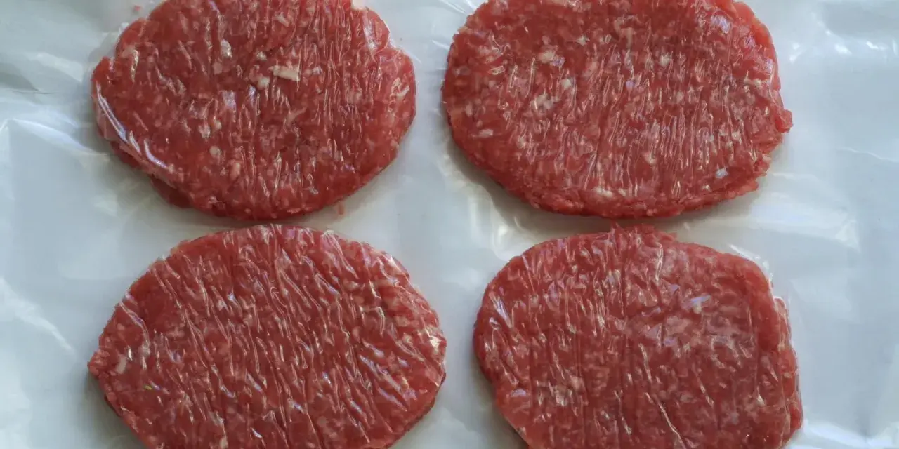 Cuatro hamburguesas de carne poco hecha, listas para cocinar y disfrutar.