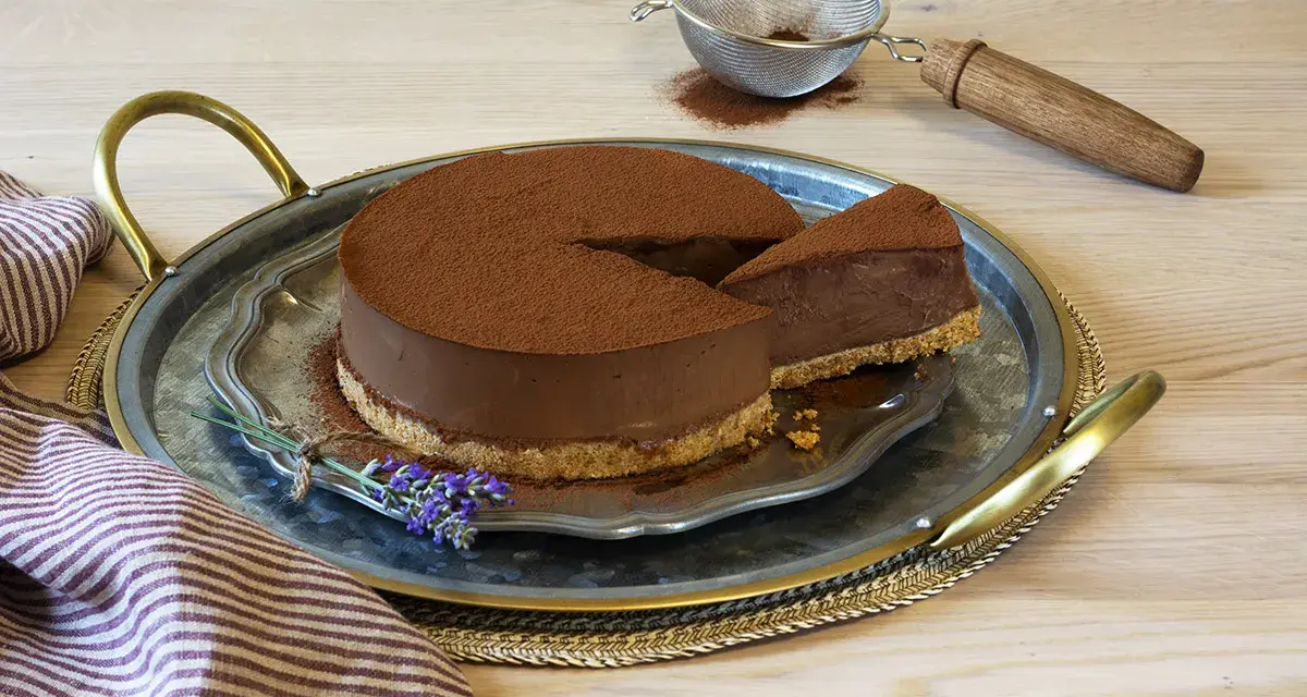 Delicioso pastel de chocolate cubierto de cacao, con una rebanada servida en una bandeja de plata, decorado con lavanda.