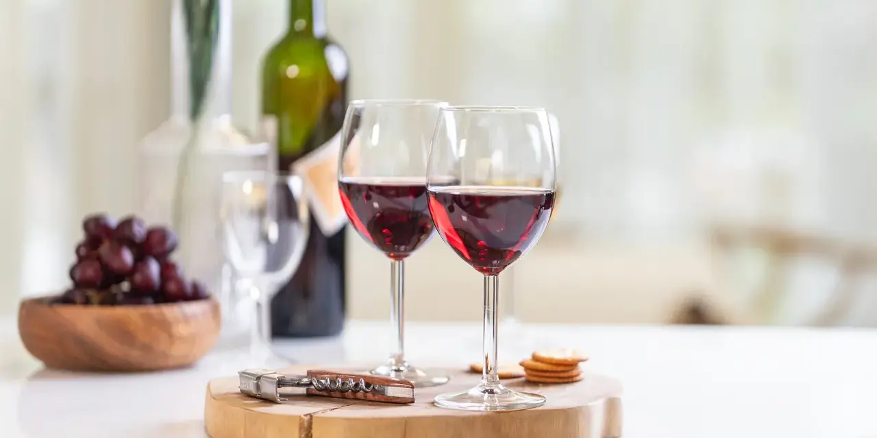 Dos copas de vino tinto, uvas y galletas, listas para disfrutar de un momento especial con los productos de la cooperativa do val.
