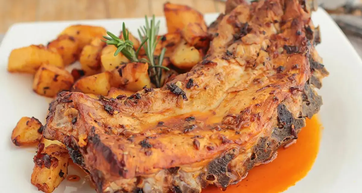 Costillas al horno con patatas doradas y romero fresco. Un plato jugoso y lleno de sabor.