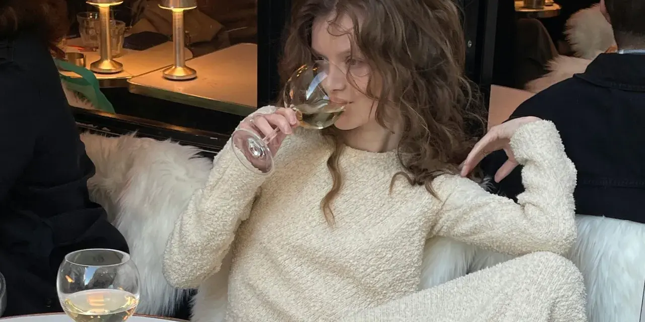 Mujer disfruta de los beneficios del vino blanco en un ambiente acogedor.