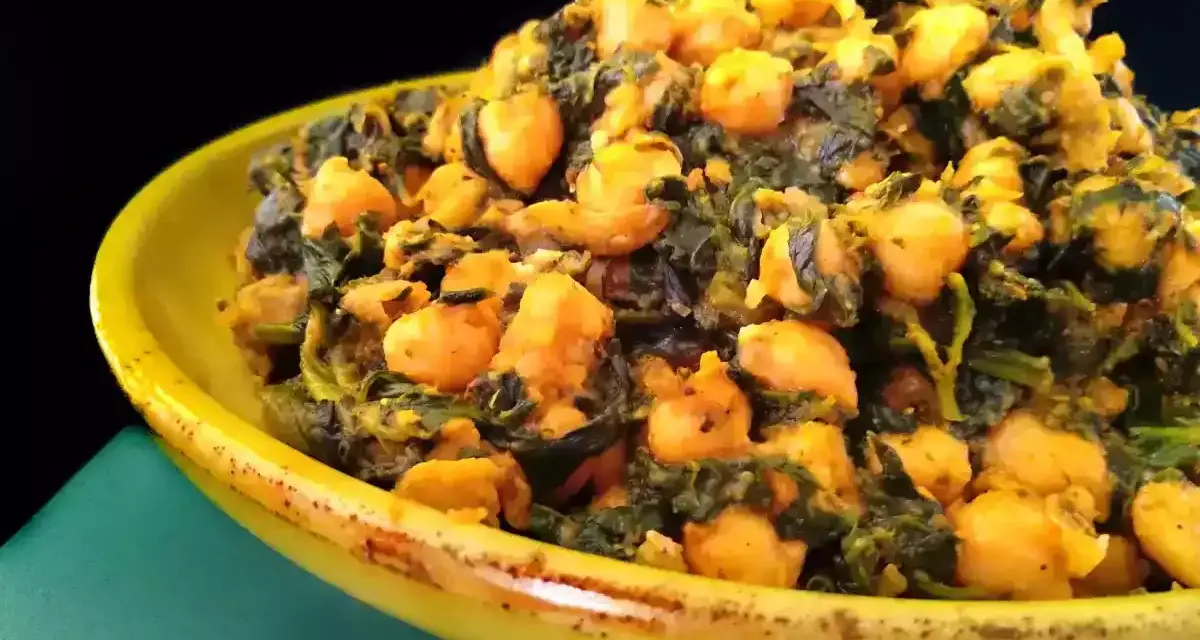 Un plato amarillo lleno de garbanzos con espinacas, un guiso saludable y sabroso.