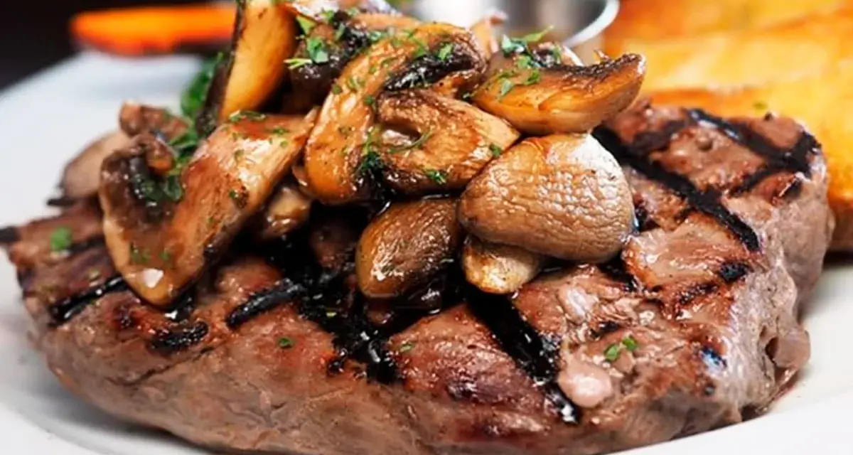Solomillo de ternera guisado con champiñones salteados y perejil picado, servido en un plato blanco.