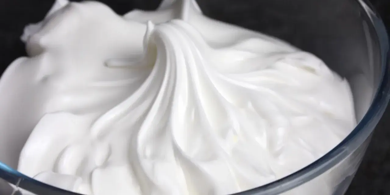 Merengue italiano esponjoso y brillante en un bol de cristal, listo para decorar postres.